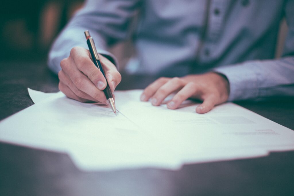 Image of hands signing some documents.